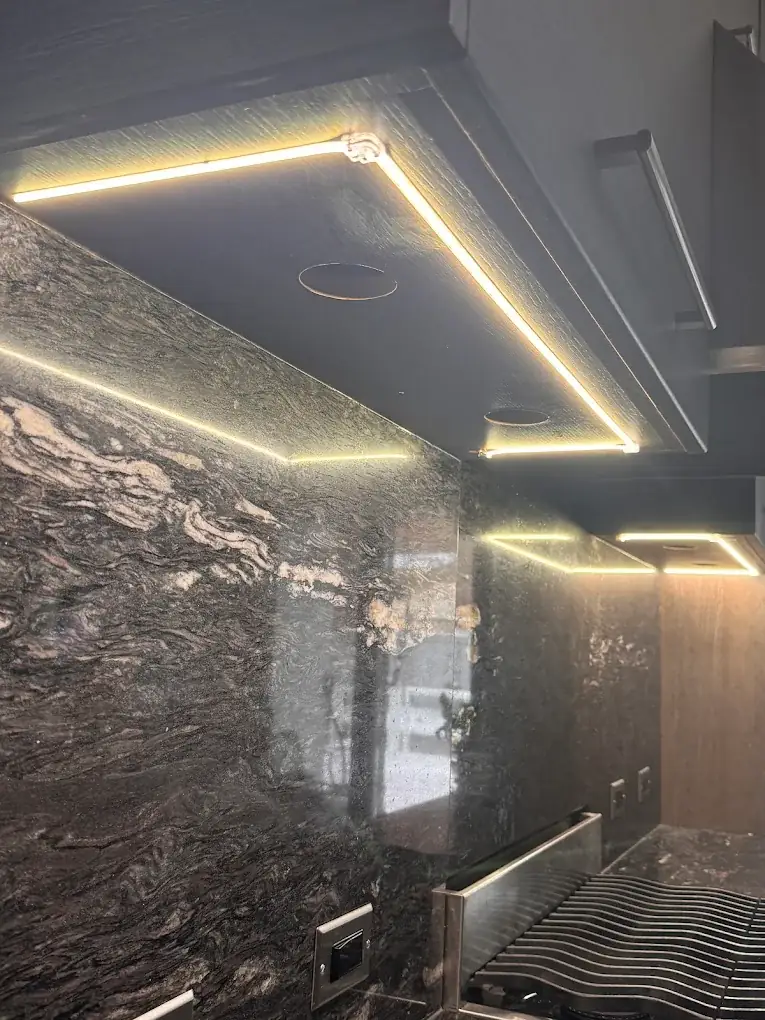 Warm LED strip lighting under cabinets washing a granite backsplash