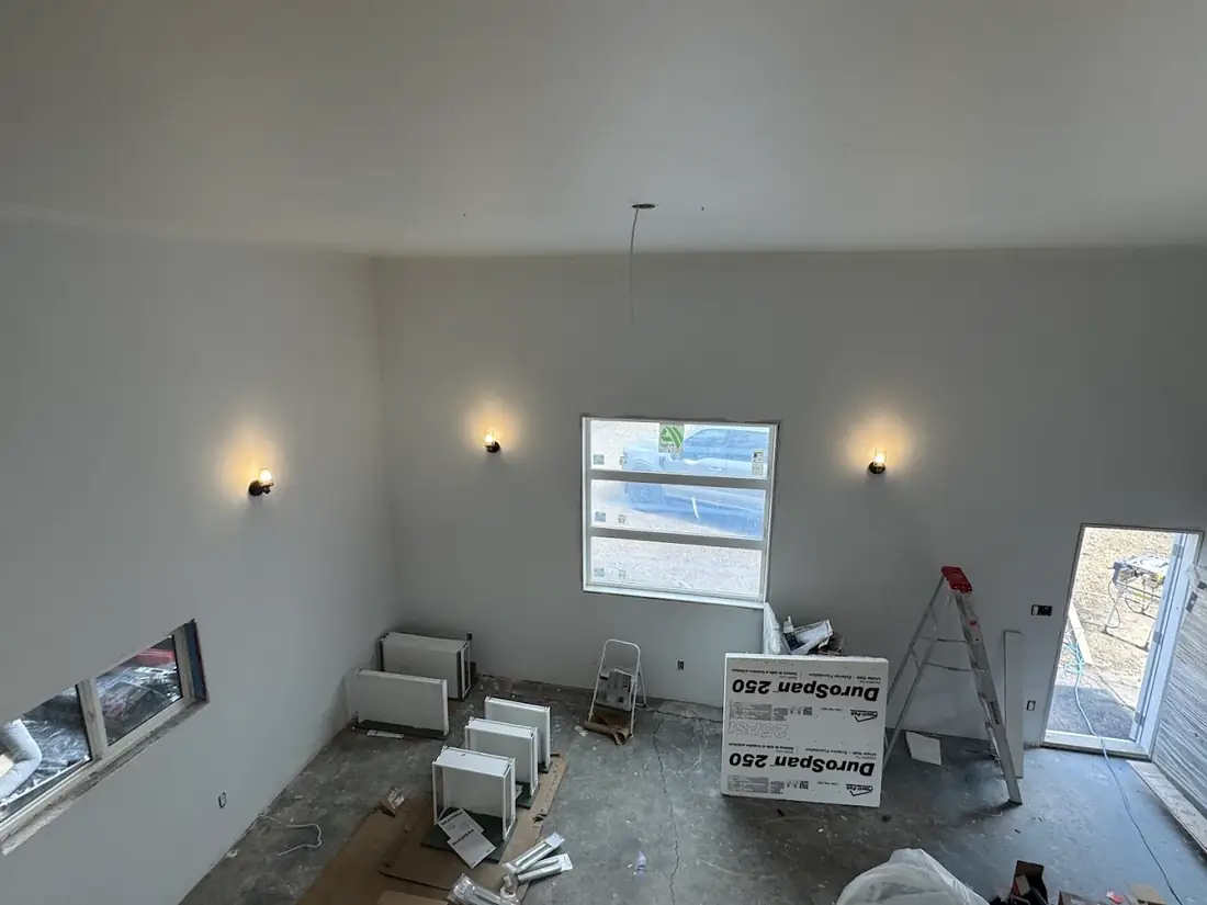 Wall sconces lit in a room under construction